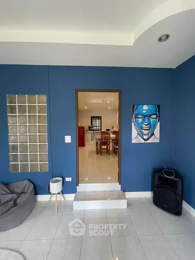 Stylish living room with blue walls and modern decor leading to a dining area.
