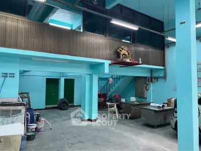 Spacious industrial-style interior with mezzanine and vibrant blue walls, ideal for creative workspace or storage.