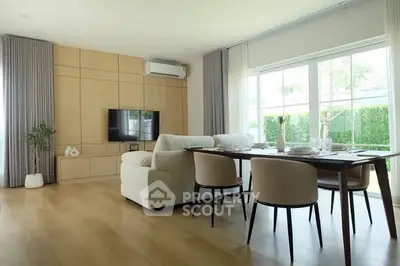 Spacious living room with elegant dining area and large windows overlooking a lush garden.