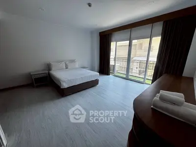 Spacious bedroom with large windows and balcony access in modern apartment.