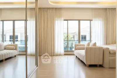 Spacious living room with elegant sofas and large windows offering abundant natural light.