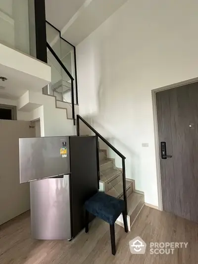 Modern interior with sleek staircase and stainless steel fridge in compact living space