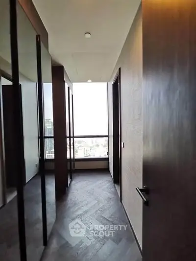 Modern hallway with large windows offering city views and sleek wooden flooring.