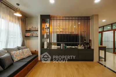 Stylish living room with modern decor and wooden flooring, featuring a cozy seating area and decorative shelving.
