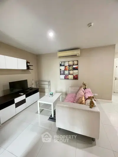 Modern living room with sleek furniture and wall-mounted TV in a cozy apartment.