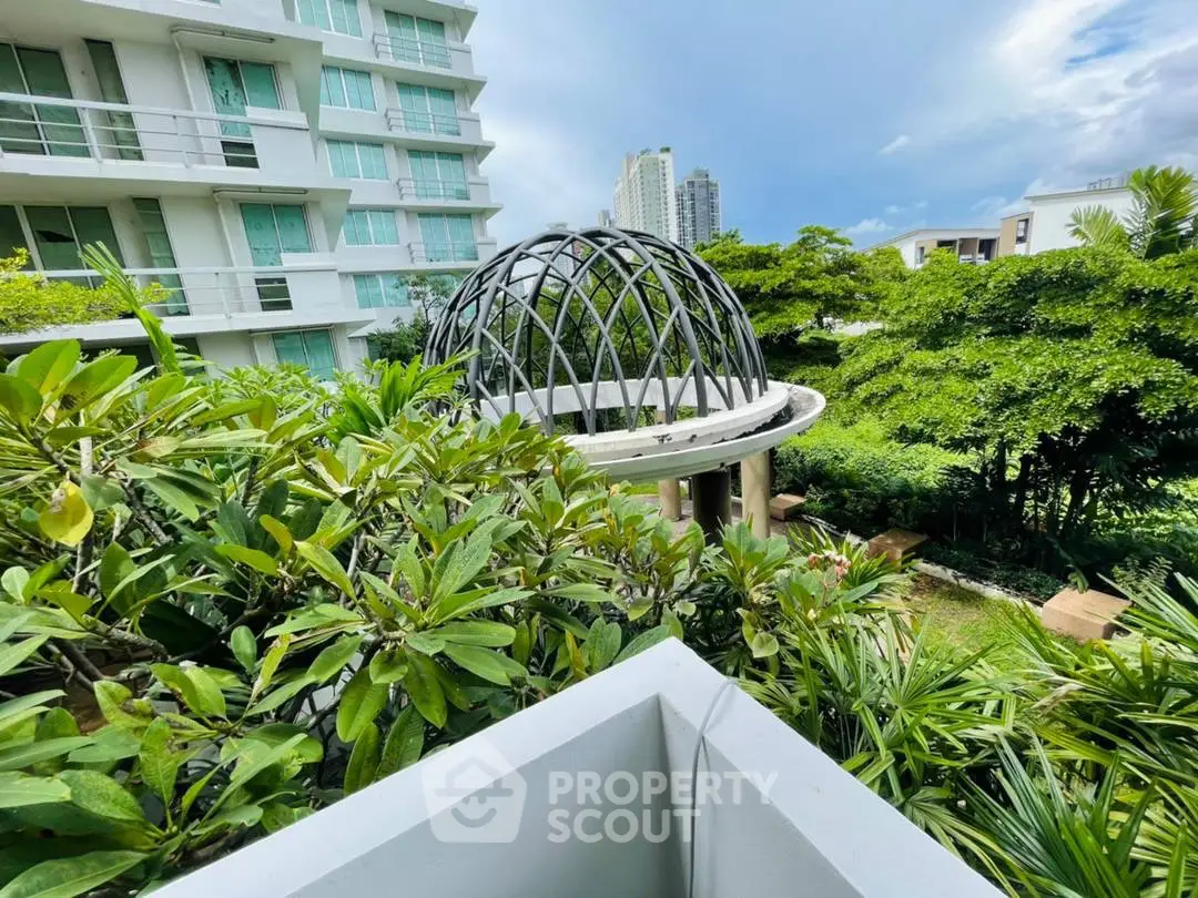 Luxurious garden view from modern apartment balcony with lush greenery and architectural dome.