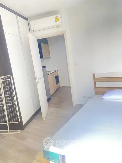 Bright bedroom with modern air conditioning and open door to kitchen area.