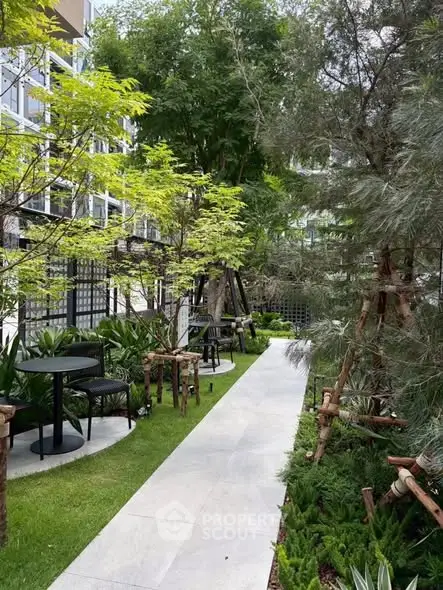 Lush garden pathway with modern outdoor seating in a residential complex.