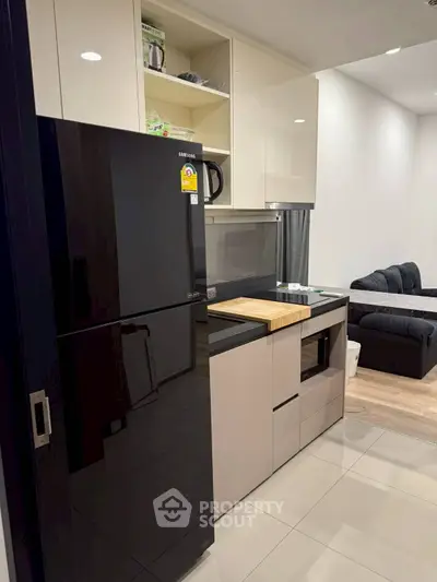 Modern kitchen with sleek black fridge and open shelving in stylish apartment