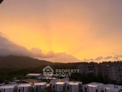 Stunning sunset view over modern residential buildings and lush green landscape.