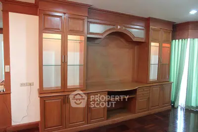 Elegant wooden built-in cabinet in a spacious living room with polished hardwood floors.