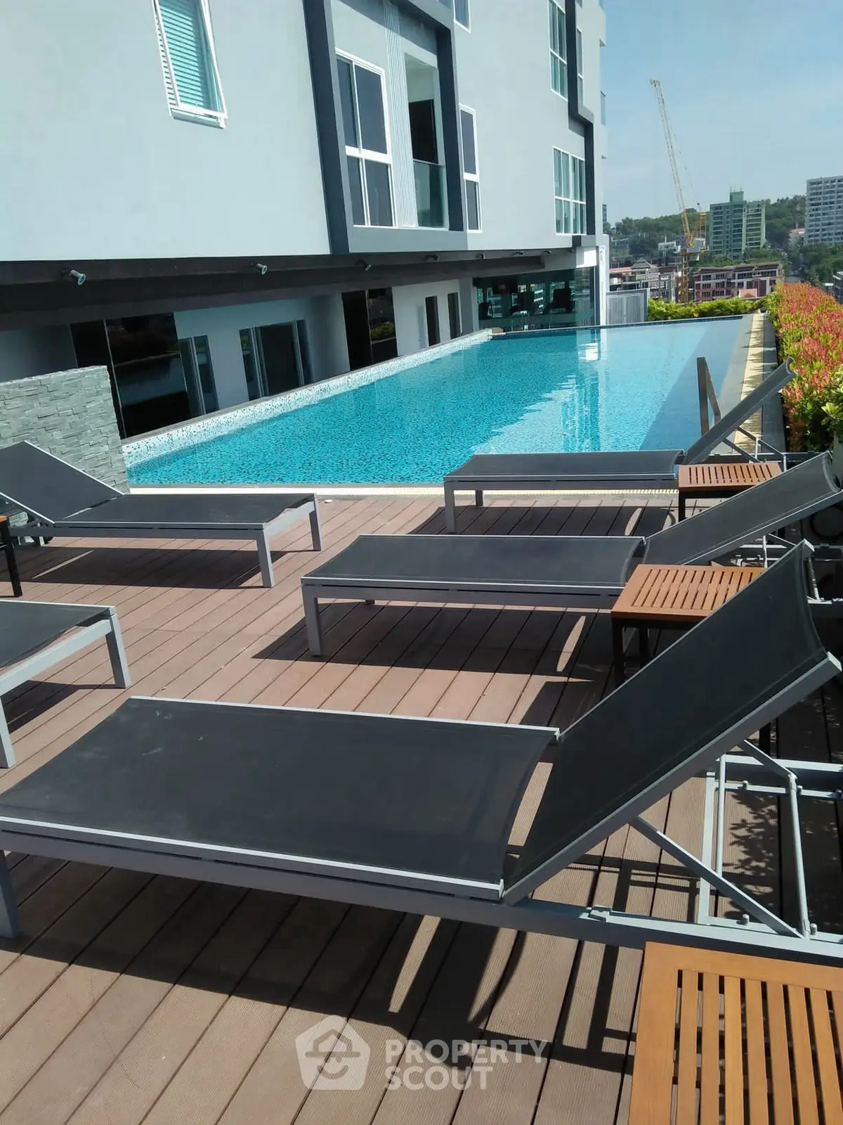 Luxurious rooftop pool area with modern sun loungers and city view, perfect for relaxation and leisure.