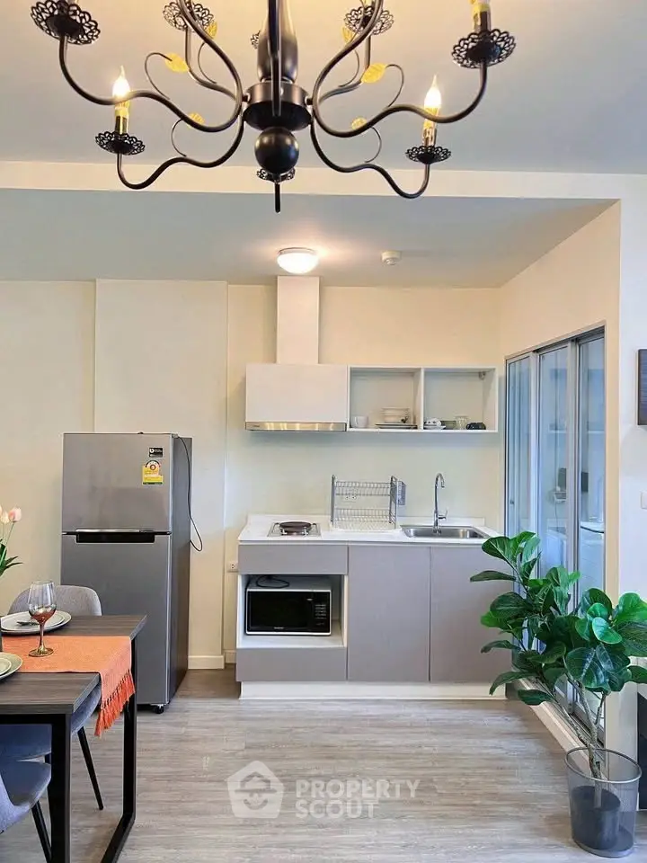 Modern kitchen with sleek appliances and elegant chandelier in a stylish apartment