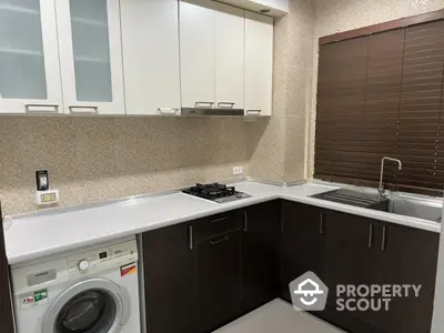 Modern kitchen with sleek cabinets, gas stove, and washing machine in a compact layout.