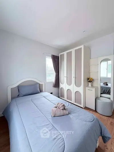 Cozy bedroom with modern wardrobe and soft blue bedding in a bright, airy space.