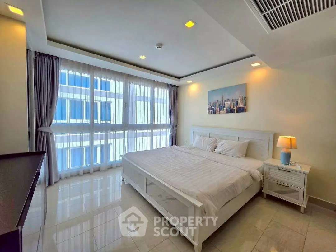 Spacious bedroom with large windows and modern decor in a luxury apartment.