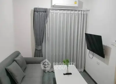 Modern living room with sleek gray sofa, wall-mounted TV, and air conditioning, perfect for cozy relaxation.