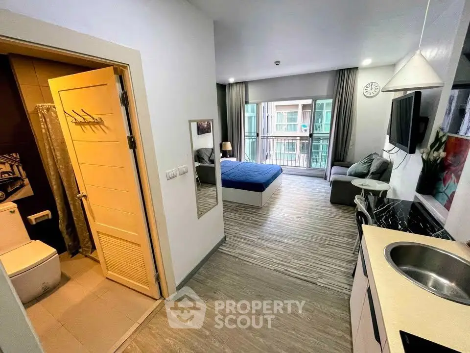 Modern studio apartment with open layout, featuring a cozy bedroom, compact kitchen, and balcony view.