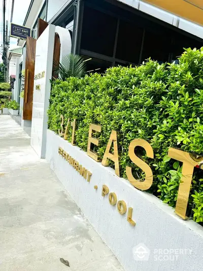 Modern building entrance with lush greenery and stylish signage