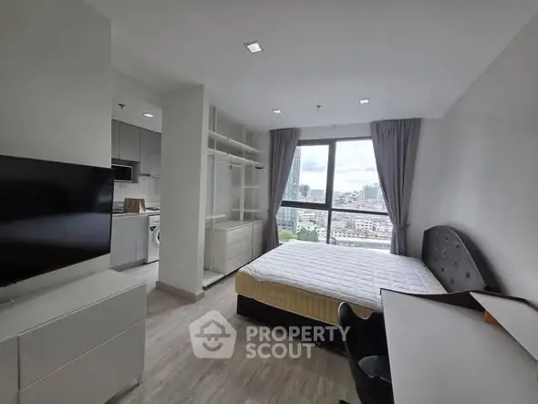 Modern studio apartment with city view, featuring a cozy bedroom and compact kitchen area.