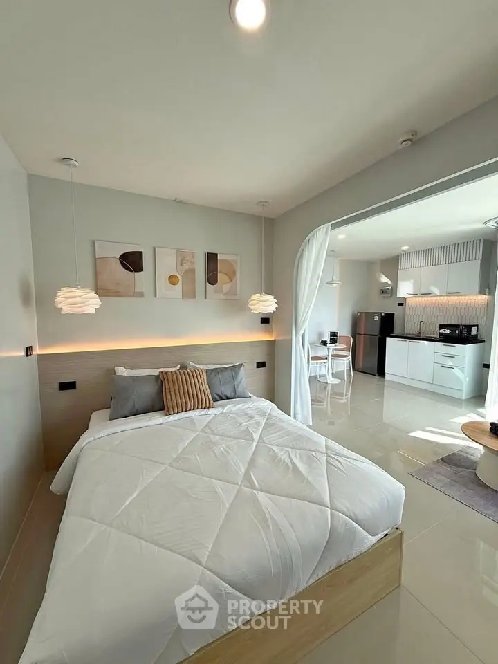 Modern bedroom with open layout to kitchen, featuring stylish decor and cozy ambiance.