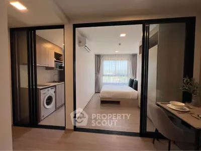 Modern apartment with open kitchen, washing machine, and cozy bedroom with large window.