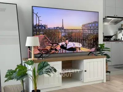 Modern living room with stylish decor and large TV displaying a scenic view, open kitchen in background.
