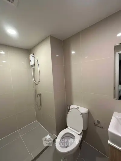 Modern bathroom with sleek tiles and shower area in contemporary apartment.