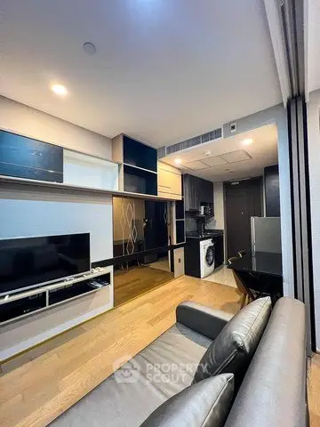 Modern living room with open kitchen and sleek design, featuring a washing machine and stylish furniture.
