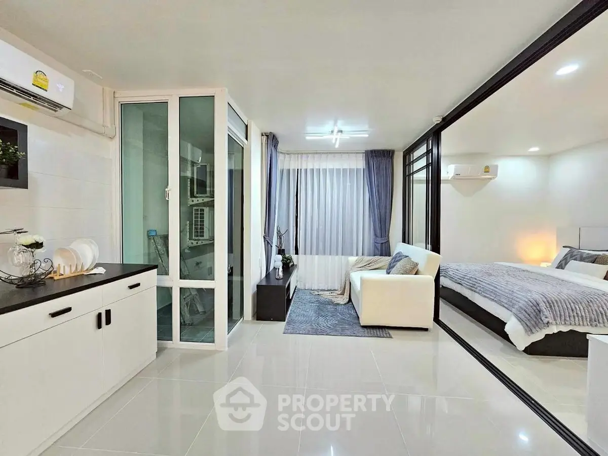 Modern open-plan living room with glass partition and cozy bedroom