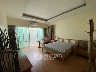 Spacious bedroom with modern decor and natural light, featuring a large bed and wooden furniture.