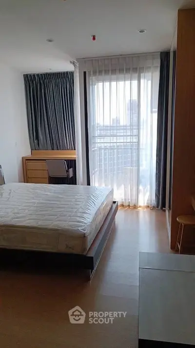 Modern bedroom with large window and city view, featuring a comfortable bed and stylish furnishings.
