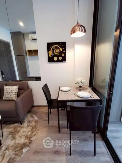 Modern living room with dining area, stylish decor, and large window for natural light.