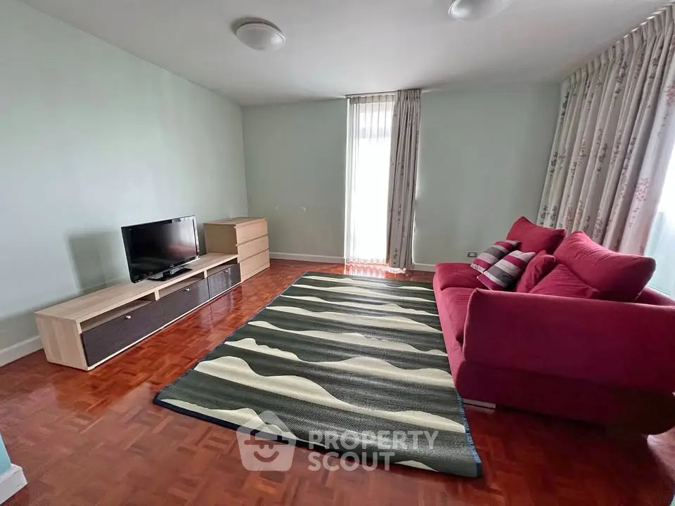 Spacious living room with modern furniture and natural light, featuring a stylish rug and comfortable seating.
