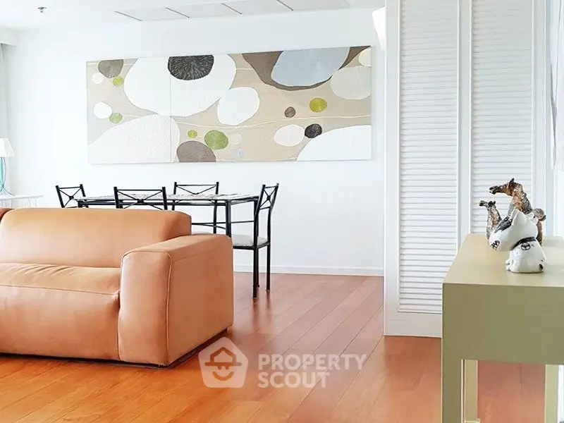 Modern living room with stylish decor and wooden flooring, featuring a cozy leather sofa and elegant dining area.