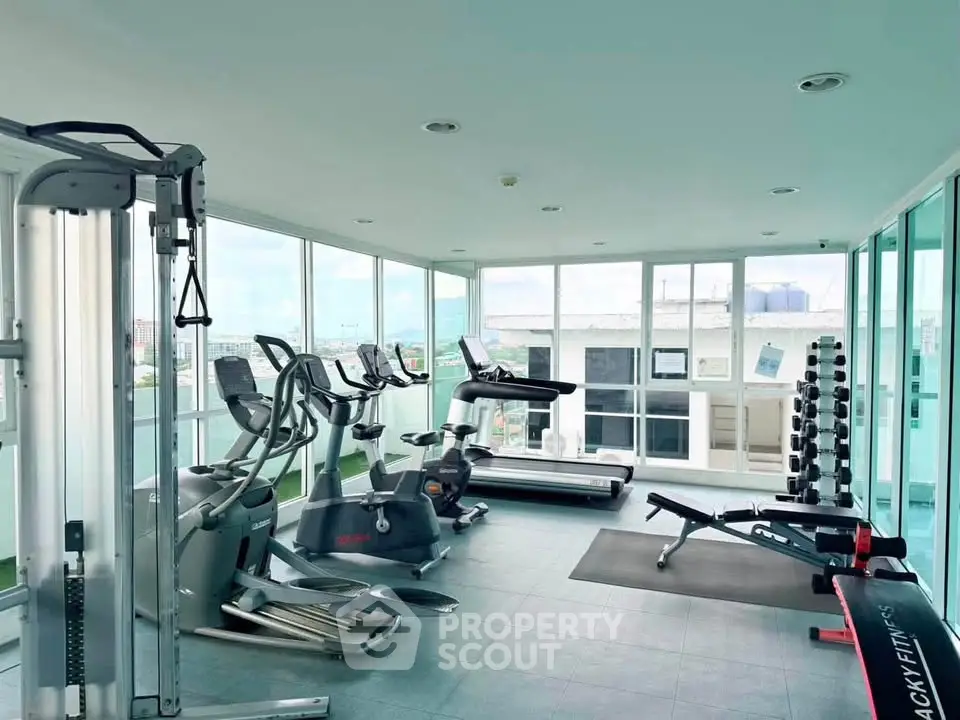 Modern gym with panoramic windows and state-of-the-art fitness equipment in a luxury building.