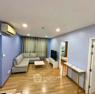 Spacious modern living room with sleek furniture and wooden flooring, perfect for relaxation and entertainment.