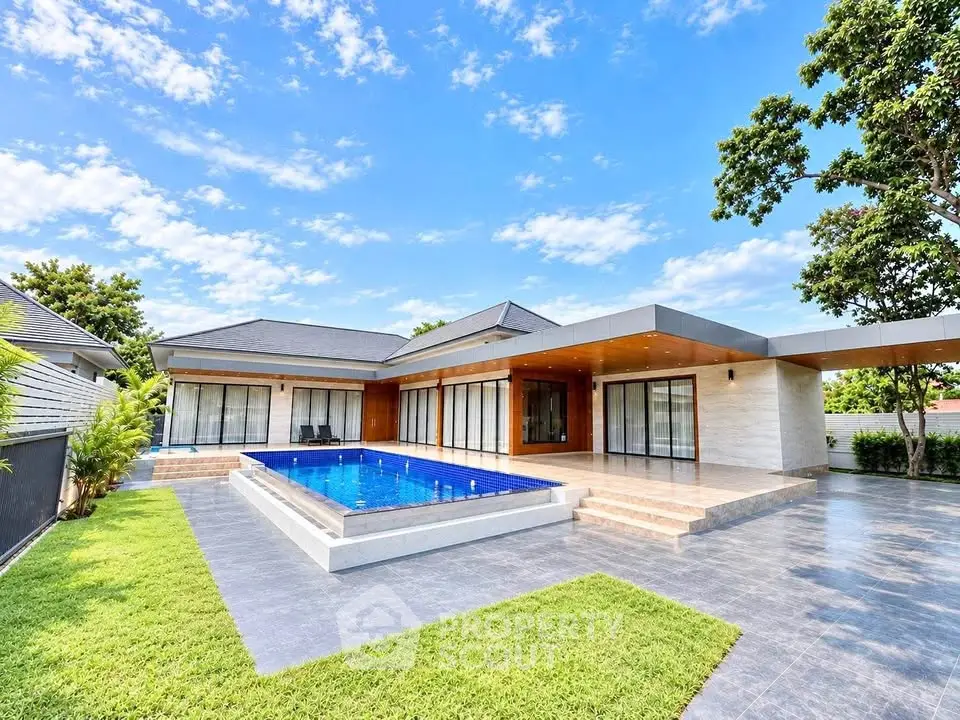 Luxurious modern villa with private pool and spacious patio under a clear blue sky.