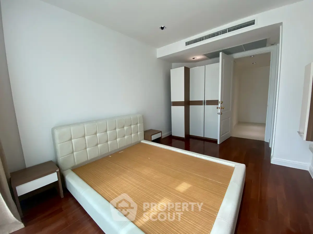 Spacious bedroom with modern design and wooden flooring in a luxury apartment.