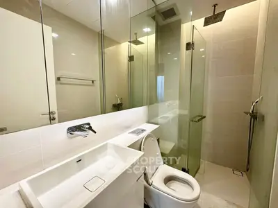 Modern bathroom with glass shower and sleek fixtures in luxury apartment.