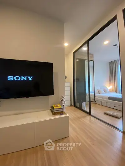 Modern living room with sleek TV setup and view into cozy bedroom