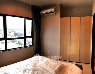 Modern bedroom with large window and city view, featuring a sleek wardrobe and air conditioning.