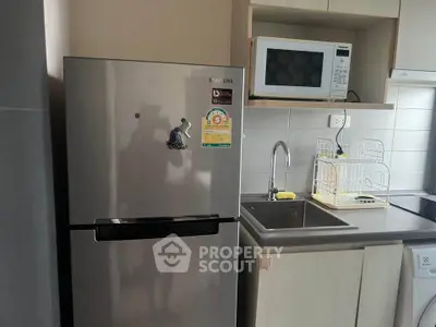 Modern kitchen with stainless steel fridge, microwave, and sleek cabinetry.