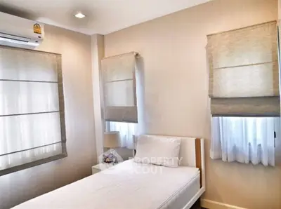 Cozy bedroom with natural light and modern decor, featuring a single bed and air conditioning.