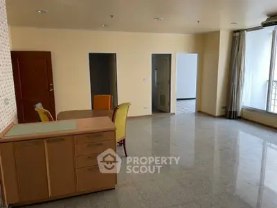 Spacious living room with large windows and dining area in modern apartment.