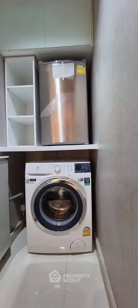 Compact laundry area with modern washing machine and storage space