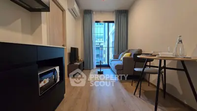 Modern living room with balcony view, featuring cozy seating and stylish decor in a compact apartment.