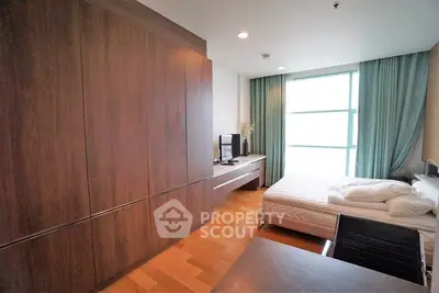 Modern bedroom with large window and wooden flooring in a stylish apartment