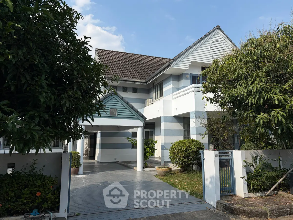 Charming two-story house with striped facade and lush greenery