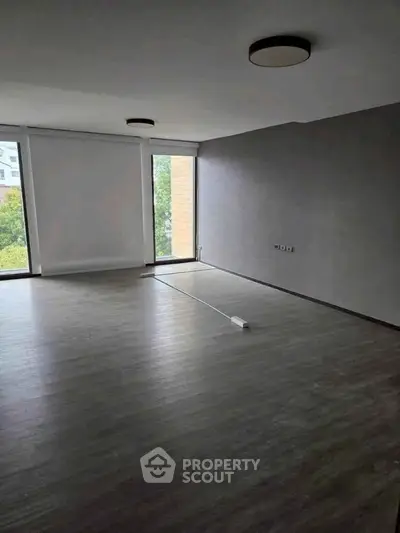 Spacious empty room with large windows and modern lighting, perfect for customization.